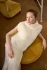 A woman is sitting on a yellow stool, leaning against it. She is wearing a white knitted vest and a light-colored skirt. The background shows a wooden floor and a yellow armchair. Produktbild-Vorschau