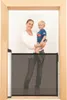 A woman is holding a child in front of a baby gate. Náhľad obrázku produktu