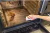 A hand is cleaning a very dirty oven with a white sponge. Produktbild-Vorschau