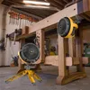 Two portable fans in a workshop setting, one on a tripod and one mounted on a workbench. Náhľad obrázku produktu