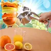 A hand is using a manual juicer to squeeze juice into a glass, surrounded by various fruits and a background of more fruits and a bright sky. Náhľad obrázku produktu