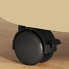 Close-up of a black caster wheel with a lock mechanism attached to a beige surface, resting on a wooden floor. Produktbild-Vorschau
