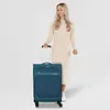 A woman stands next to a teal suitcase. Podgląd zdjęcia produktu
