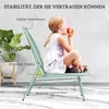 A young girl sits on a green chair and eats an apple, with a plant in a pot to the left. Náhľad obrázku produktu
