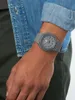 A person wearing a grey watch and a denim shirt. Náhled obrázku produktu