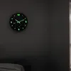 A glow-in-the-dark wall clock with a space theme is mounted on a dark gray wall above a bed. Náhled obrázku produktu