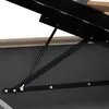 A close-up view of the mechanical support system of a bed frame, showing a gas strut and metal brackets. Produktbild-Vorschau
