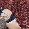 A close-up view of a rug with pillows and a blanket. Produktbild-Vorschau