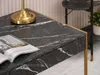 A close-up view of a black marble desk with gold accents, featuring an open book and a brass lamp. Voir les images du produit