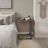 A bedside table next to a bed with a mug and a plant on it. Voir les images du produit
