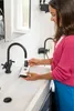 A woman is cleaning a device under a faucet in a bathroom sink. Anteprima dell’immagine prodotto
