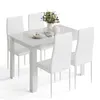 A white dining table with four white chairs, set with a plate, cutlery, a teapot, and a vase of flowers. Produktbild-Vorschau