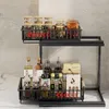 A two-tier black metal kitchen organizer shelf filled with various bottles and jars. Voir les images du produit