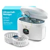 A product shot showcasing an ultrasonic cleaner with jewelry and eyeglasses inside, along with a separate basket containing a wristwatch. A product box is visible in the background. Produktbild-Vorschau