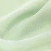 A close-up view of light green fabric with soft folds and shadows, highlighting the texture and drape. Produktbild-Vorschau