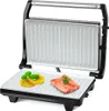 An open contact grill with food items on the bottom plate. Voir les images du produit