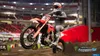 A motocross rider performing a jump on a dirt track inside a stadium. Produktbild-Vorschau