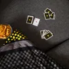 A top-down view of playing cards and a bowl of chips on a sofa, with a blanket. Produktbild-Vorschau
