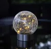 A close-up shot of a decorative glass orb light with embedded LED lights, sitting on a reflective surface. Produktbild-Vorschau