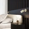 A bedroom scene with a bed, bedside table, and wall lighting. Anteprima dell’immagine prodotto
