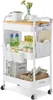 A white rolling cart with three shelves, a wooden top, and various items on it, including books, jars, bottles, and office supplies. Produktbild-Vorschau