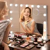 A woman is applying makeup in front of a Hollywood-style vanity mirror with lights. Various makeup products are laid out on the table. Anteprima dell’immagine prodotto