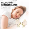 A woman is sleeping in bed with earbuds in her ears, and a pair of earbuds are shown in the foreground. Produktbild-Vorschau