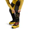 La Sportiva Olympus Tech Down Pant in Schwarz mit gelben Akzenten; getragen von einem Mann; der die Hose anpasst. Podgląd zdjęcia produktu
