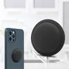 A black silicone case for an Apple AirTag is shown next to an iPhone with a pop socket attached. Anteprima dell’immagine prodotto