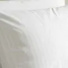 A close-up view of a white pillowcase with subtle vertical stripes. Produktbild-Vorschau