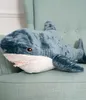 A plush shark toy lying on a light green armchair. Podgląd zdjęcia produktu