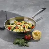 A stainless steel frying pan filled with pasta, spinach, and cherry tomatoes, with a bundle of uncooked pasta, a tomato, and spinach leaves on the side. Podgląd zdjęcia produktu