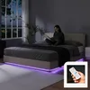 A woman is reading a book in bed at night, with ambient purple LED lighting under the bed frame. Produktbild-Vorschau