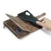 A hand is shown placing a phone case into a brown leather wallet with a zipper and card slots. Produktbild-Vorschau