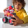 A young boy is playing with a red and gray toy fire truck with a character on it. Produktbild-Vorschau