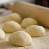 Dough balls are arranged on a surface with a rolling pin in the background. Podgląd zdjęcia produktu