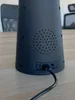 Close-up view of the back of a black conical lamp, showing a speaker grille and connection ports with a cable plugged in. Anteprima dell’immagine prodotto