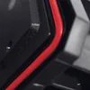 A close-up view of a black product with a red trim, showing texture and detail. Produktbild-Vorschau