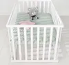 A white baby playpen with a green quilted mat and two stuffed toys. Náhled obrázku produktu