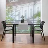 A balcony setting with a table and chairs, overlooking a building. Produktbild-Vorschau