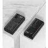 Two black power banks are displayed on white pedestals with a marble-patterned background. Produktbild-Vorschau