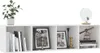 A white wall-mounted shelf unit displaying books, framed pictures, a globe, and decorative items. Náhľad obrázku produktu