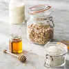 A still life arrangement of ingredients for breakfast or baking, including milk, granola, honey, and shredded coconut, set on a marble countertop. Anteprima dell’immagine prodotto