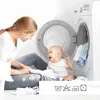 A mother and baby are sitting on the floor next to an open washing machine, with laundry around them. Produktbild-Vorschau