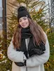 A woman wearing a winter hat and scarf stands in front of a decorated Christmas tree with lights. Voir les images du produit