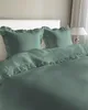 A bed with mint green bedding and pillows. Produktbild-Vorschau