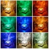 A collage of nine images showcasing a cube-shaped LED lamp projecting different colored light patterns onto a background. Produktbild-Vorschau
