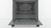 An open oven with its door pulled down, revealing the interior cavity with a fan visible at the back. Produktbild-Vorschau