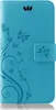 A blue flip cover phone case with a floral and butterfly design. Produktbild-Vorschau