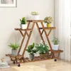 A wooden plant stand with multiple tiers holding various potted plants and a bouquet of flowers. Produktbild-Vorschau